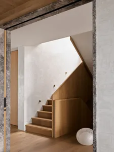 Modern staircase with wooden steps and railings against a white wall.