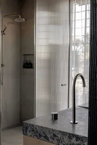 A contemporary bathroom featuring glass walls and a marble countertop.