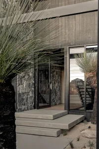 Concrete steps leading to a modern entrance with stone walls and glass door.