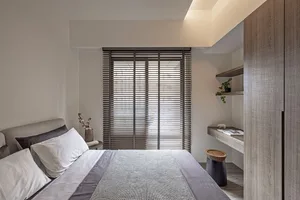 Minimalist bedroom with a wooden bed frame and window blinds.