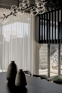 A modern dining room featuring a glass chandelier with a minimalist design.