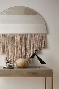 A modern decorative mirror with a metallic fringe hanging from the bottom.