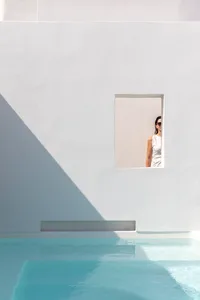 A minimalist design featuring a concrete pool side with a woman looking through a window.