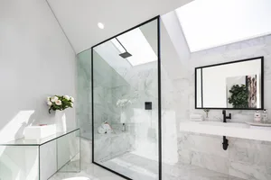Modern bathroom featuring a minimalist design with marble fixtures and a skylight