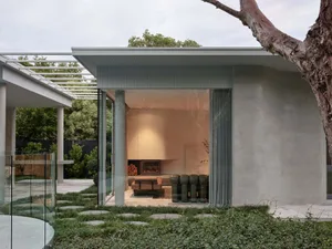 A modern living room with a concrete wall, large windows, and a cozy seating area.
