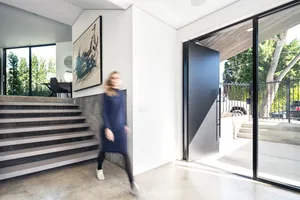A blurred image of a modern residential interior with a concrete staircase and large sliding door.