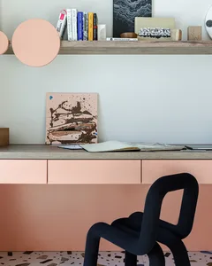 Modern home office setup featuring a wooden desk with a terrazzo drawer, a black sculptural chair, and various books on a flo