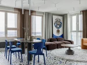 Modern living room featuring terrazzo flooring, minimalist brown furniture, and a blue and orange sofa.