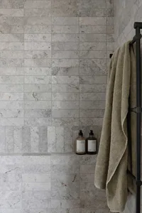 A bathroom with grey tiled walls and a grey towel hanging on a towel rack.