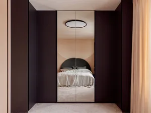 A modern minimalist bedroom featuring a black feature wall, white bed, and carpeted floor.