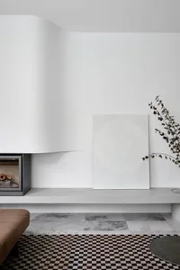 Modern minimalist interior space featuring a concrete fireplace and geometric artwork.
