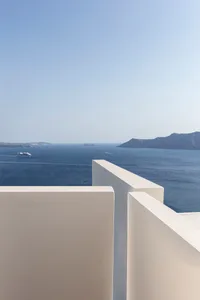 A white concrete balcony overlooking the sea on a clear day.