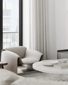 Modern living room with white fabric and leather furniture, light gray curtains, and a sleek, white round coffee table.