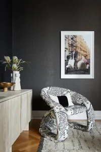 A stylish lounge chair with a vibrant black and white pattern sits in a modern, industrial-themed living room.
