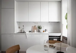 A minimalist white kitchen with modern cabinets and a clean, uncluttered design.