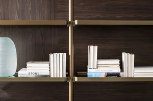 A close-up view of a modern bookshelf made of wood with metallic accents and stacks of books.