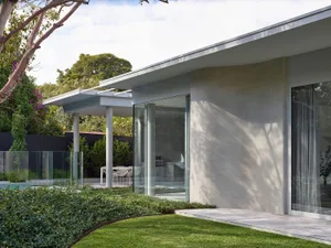 A modern house featuring a concrete exterior with large glass windows and a spacious garden.