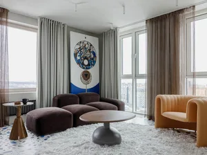 A modern living room featuring contemporary furniture with minimalist style, upholstered couches, and a round wooden coffee t