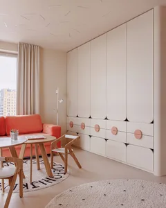 A minimalist modern interior design with a white furniture set and orange accents.