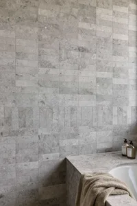 Modern minimalist bathroom with stone tile walls and a clean, uncluttered design.
