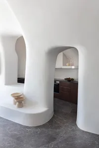A modern, minimalist kitchen with white curved walls and marble countertops, featuring dark wood cabinets and a sleek, contem