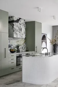 A sleek, minimalist kitchen featuring marble countertops and backsplash, modern appliances, and a curved island.