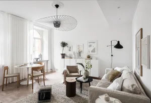 A minimalist living room with a concrete floor, white walls, and a large window.