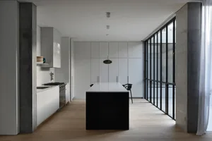 Modern residential kitchen featuring white marble countertops, concrete walls, and glass doors.