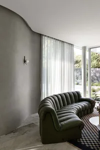 A modern sofa upholstered in green leather with a textured surface, positioned in a well-lit residential space.