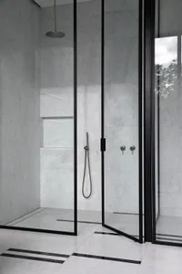A minimalist bathroom with white marble walls and black fixtures.