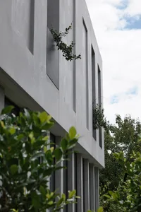 Modern exterior of a building made of concrete with green plants growing through the walls.