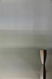 A minimalist metal sculpture against a grey gradient background.