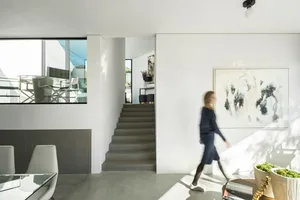 A minimalist living room with a concrete floor, white walls, and a large window.