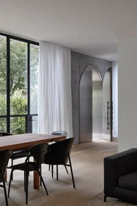 A modern interior space featuring a dining area with wooden table and black chairs, a couch, and a minimalist design with con