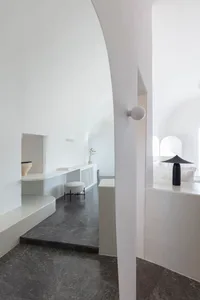 A minimalist interior with white marble flooring and walls, featuring a modern design with clean lines and a single black lam