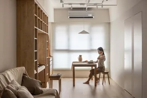 A minimalist living room featuring wood furniture and a large window with blinds.