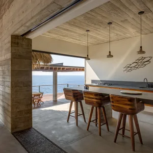 Modern minimalist residential kitchen featuring concrete and terrazzo materials with ocean views.