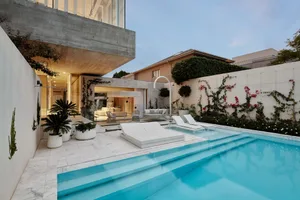 Modern backyard featuring a concrete pool with a contemporary design, surrounded by white walls adorned with climbing plants