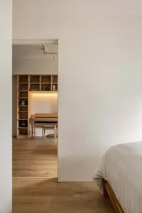 A modern bedroom featuring a wooden bed against a white wall with a wooden shelving unit and a piano.