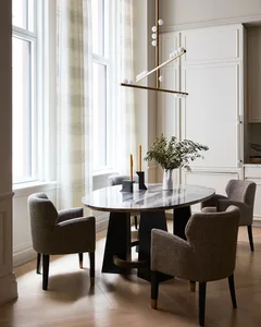 A contemporary dining room with a black and white table, grey upholstered chairs, and a modern chandelier.