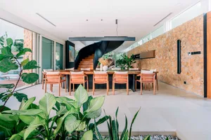 Modern dining room with stone walls and wooden dining table surrounded by orange cushioned chairs.