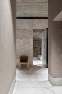 A modern entryway with marble flooring and a mix of concrete and wood materials.