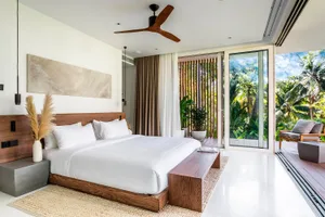 A minimalist bedroom with a wooden bed frame, white bedding, and large windows overlooking lush greenery.