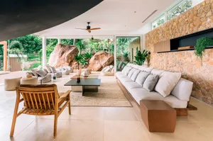 A modern minimalist living room with a concrete floor and reflection from a large window, featuring sleek furniture and natur