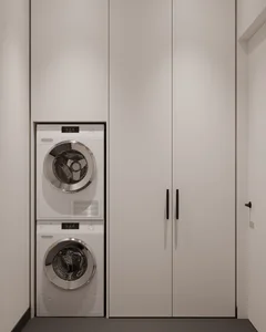 A minimalist utility room with white paneling, featuring a stacked washer and dryer unit.