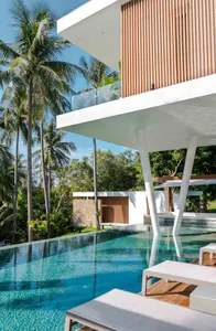 Modern patio area with wood and metal structures, featuring a glass poolside enclosure and a pergola