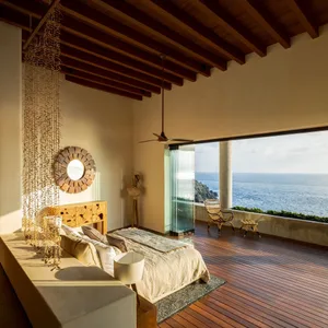 Modern residential bedroom with wooden floors and a view of the ocean.