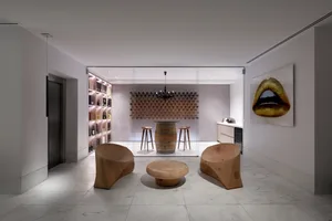 A modern wine tasting room featuring a barrel table, stools, wine bottles, and a large wine collection on the wall.