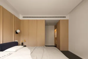 A minimalist bedroom with wooden paneling and a neatly made bed.