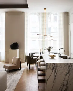 A modern, minimalist kitchen with a marble countertop, featuring sleek furniture and a hanging light fixture.